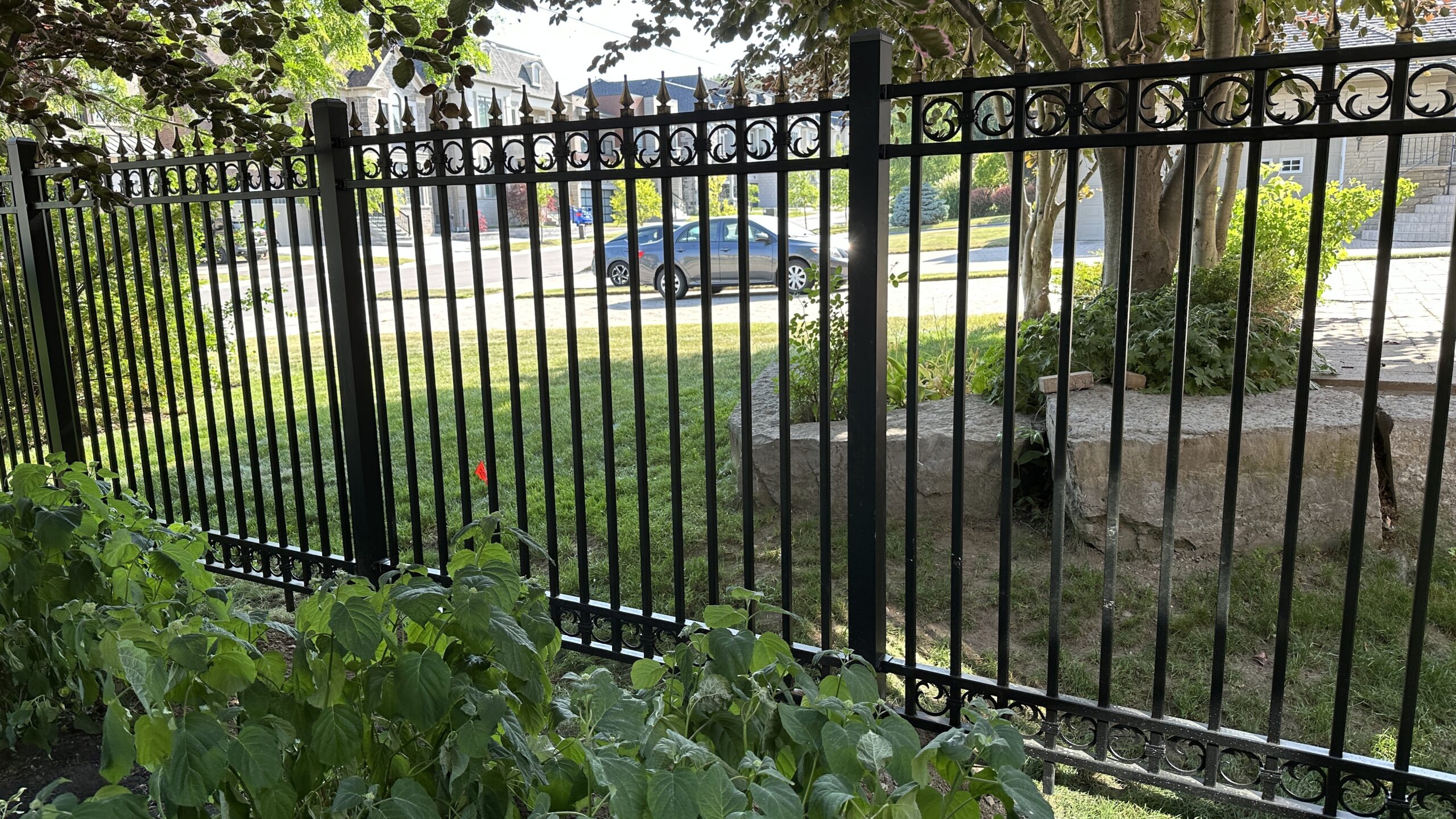 Black metal fence with pointed tops enclosing a garden area. Black metal fence with pointed tops enclosing a garden area.