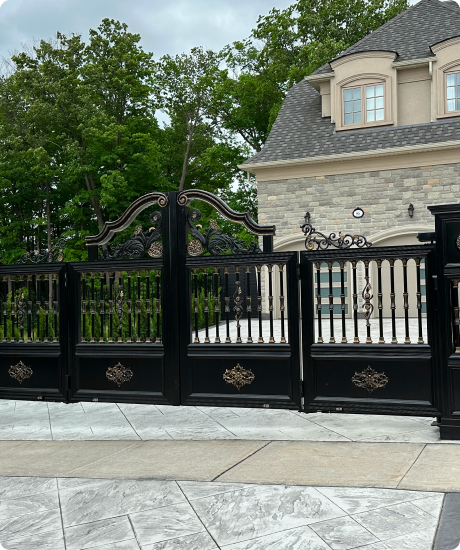 Elegant black wrought iron gate in front of a stone mansion.
